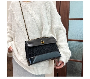 Close-up of black quilted shoulder bag with gold chain strap and turn-lock closure