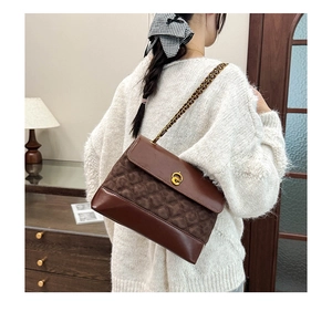Close-up of brown quilted leather handbag with gold chain strap and metal turn-lock closure