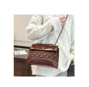 Close-up of brown quilted leather and suede shoulder bag with golden chain and clasp