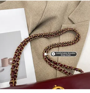 Detail of burgundy leather handbag featuring a gold metal chain strap and sleek finish