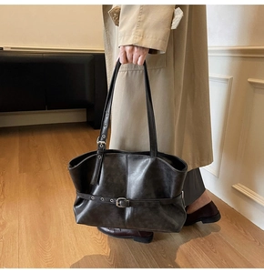 Detail of dark grey tote bag with vintage matte texture and silver buckle straps