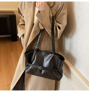 Detail view of large dark brown tote bag with adjustable straps on a trench coat