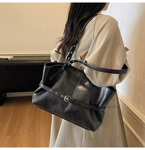 Chic black leather tote bag with silver buckle details shown on a model in a warm room