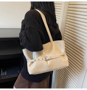Detailed view of cream leather tote bag featuring a silver buckle strap and matte texture