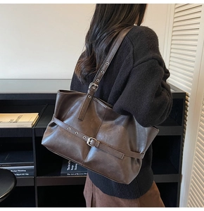 Detail of dark brown matte leather tote with adjustable buckle straps on a model