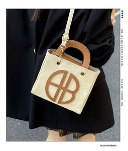 Detail view of contrast stitching and circular logo on beige and brown tote bag