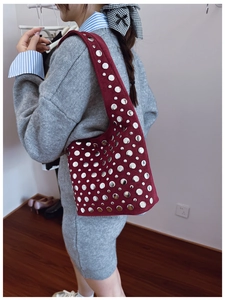 Dettaglio della borsa tote in pelle scamosciata bordeaux con borchie metalliche argentate lucide