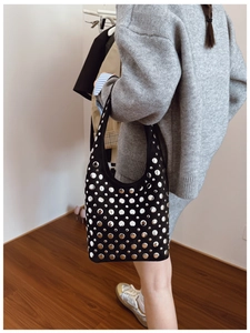 Dettaglio delle borchie argentate sulla borsa hobo nera in camoscio stile punk