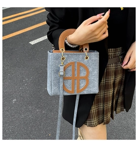 Detail of grey felt tote bag with brown leather handles and a large B-letter cutout design