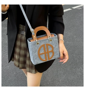 Detail of felt tote bag featuring leather AB letter patchwork and round top handles