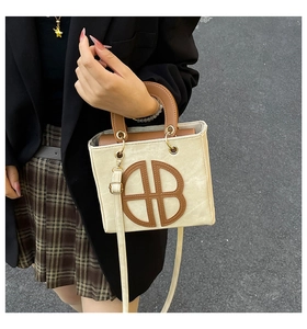 Detail of canvas tote bag with AB leather patch and brown leather handle on a grey background