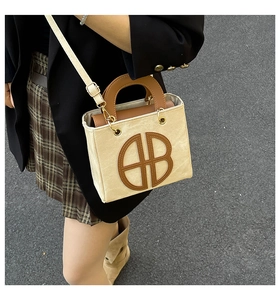Detailed shot of beige canvas crossbody bag with round leather logo and dual handles