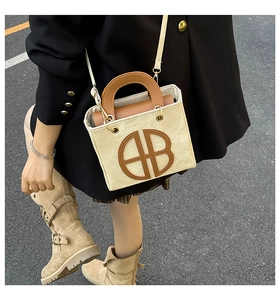 Detail of canvas tote bag with AB lettering, brown leather trim and shoulder strap