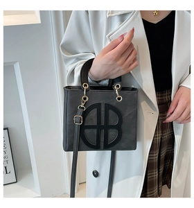 Close-up of stylish grey handbag with black interlocking logo and gold hardware detail