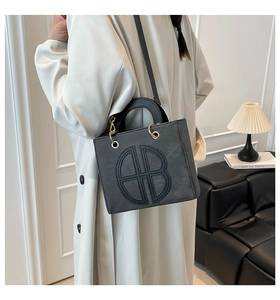Detail of black tote bag featuring decorative circular stitching and gold-tone hardware