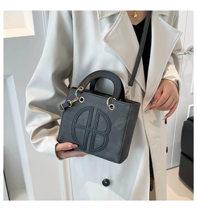 Detail of grey suede tote bag with geometric embossed logo and gold hardware accents