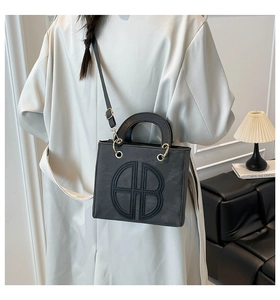 Detail shot of a black matte crossbody bag featuring an embossed HB circular logo