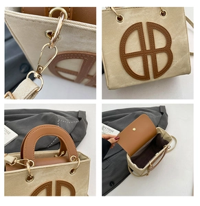 Detail view of beige canvas tote with brown leather accents and gold hardware