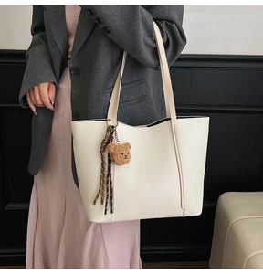 Detail of off-white lychee grain leather tote bag with braided rope and bear charm detail