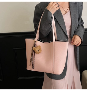 Detail of pink pebbled leather tote bag with brown bear charm and plaid ribbon accessory