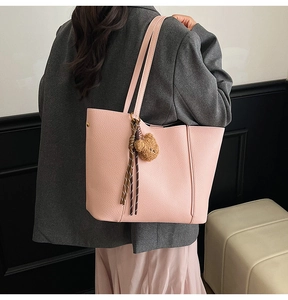Detail of light pink large tote bag featuring lychee grain leather and bear charm