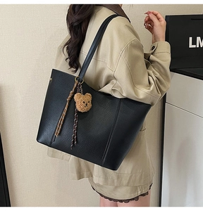 Side view of large black pebble leather tote bag with teddy charm and silk scarf
