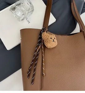 Close-up of dark brown lychee pattern tote bag with plush bear charm and woven cord
