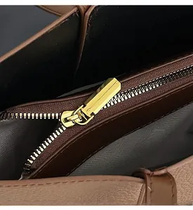 Detail view of smooth golden zipper and grey herringbone fabric lining of the tote bag