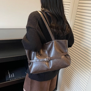 Minimalist large brown leather tote bag for women shown in a stylish shoulder carry pose