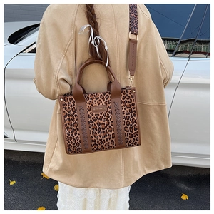 Detail der Leopard-Tragetasche mit braunen Ledergriffen und breitem Logo-Schultergurt