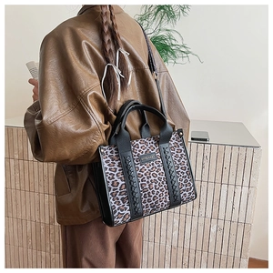 Detailansicht der Damen-Tragetasche mit Leopardenmuster, schwarzen Riemen und Metalllogo