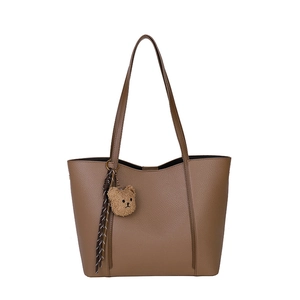 Brown litchi grain tote bag for women with a plush bear charm and woven ribbon