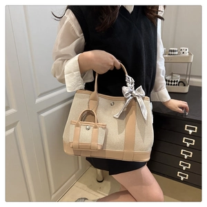 Canvas bucket bag with leather trim and decorative scarf shown on shoulder