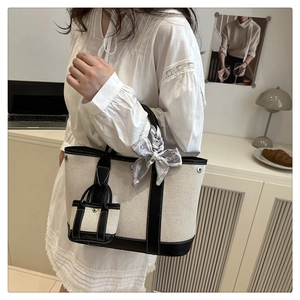 Detailed view of canvas bucket bag with silk scarf and mini pouch on model shoulder