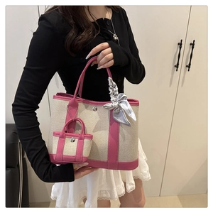Canvas bucket bag detail with pink trim, matching mini charm and satin scarf decor