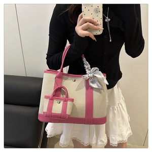 Detail of canvas tote bag with pink leather trim, small pouch, and decorative silk bow