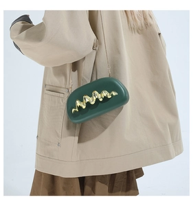 Detail der dunkelgrünen Abendtasche mit goldener Wellenschnalle und Kettenriemen