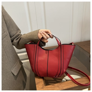 Detail of red leather bucket bag with black topstitching and gold hardware accents