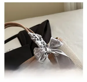 Detail showing woven texture and brown faux leather handle with silk scarf bow accent