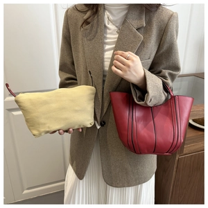 Detail showing wine red leather bucket bag and beige canvas pouch with luxury finish