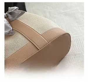 Macro detail of tan leather stitching and beige canvas with a decorative silk bow accent