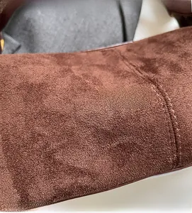 Gros plan sur la texture du daim marron et les coutures soignées de ce sac oreiller