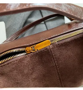 Détail macro de la fermeture éclair en métal doré et des coutures du sac marron foncé