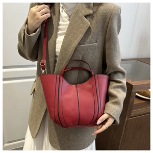 Detail of dark red matte leather tote bag with wavy rim and elegant gold metal hardware