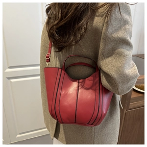 Close-up of red leather bucket bag with black vertical stripes and gold metal hardware