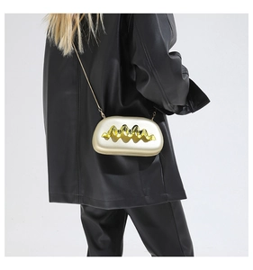 Detail der eleganten goldenen Clutch mit Wellenmuster und Metallkette am Modell