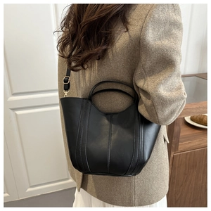 Rear view of model wearing a black PU leather bucket bag with vertical stitching detail