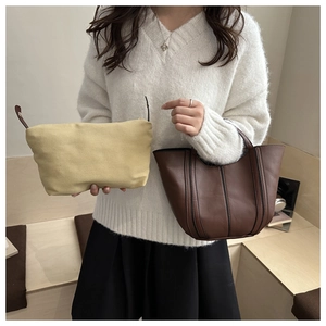 Detail of a brown leather patchwork tote bag and canvas pouch with side folding design