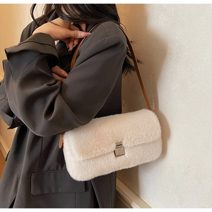 Detail of white faux fur shoulder bag with silver metal buckle and brown leather strap