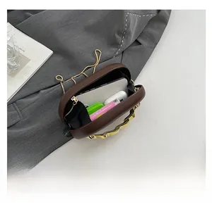 Dunkelbraune ovale Abendtasche mit goldenem Wellengriff und geräumigem Innenraum